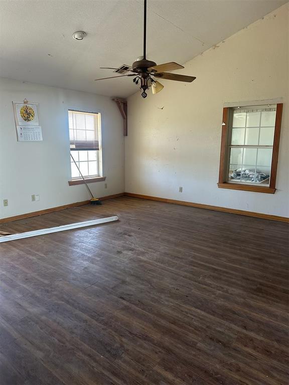 spare room with dark wood-style flooring, vaulted ceiling, and ceiling fan