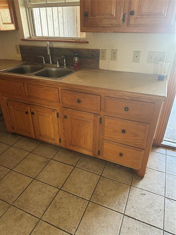 kitchen featuring brown cabinetry, light countertops, and a sink