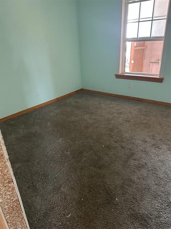 spare room with baseboards and carpet floors