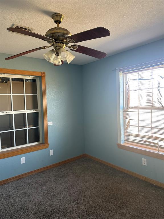carpeted spare room featuring baseboards, a textured ceiling, and ceiling fan