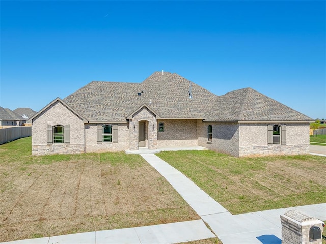 1209 Jozie Way, Tuttle, OK 73089 - french country inspired facade featuring brick siding, a shingled roof, a front lawn, and fence