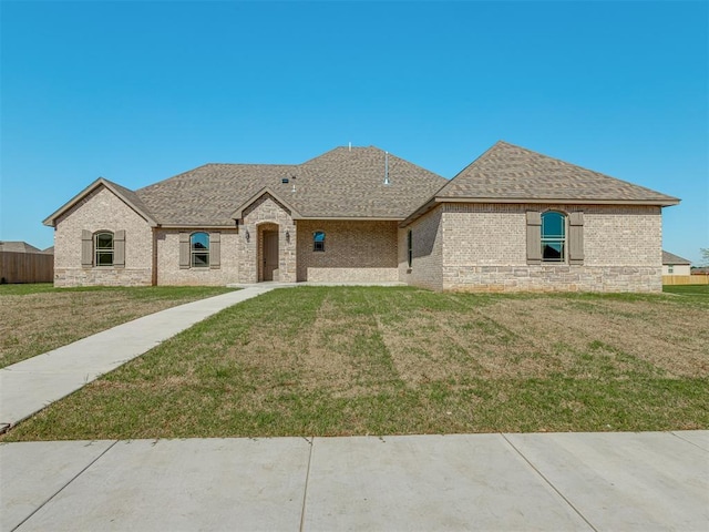 1209 Jozie Way, Tuttle, OK 73089 - french country inspired facade with brick siding, roof with shingles, fence, and a front yard