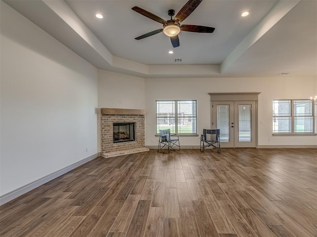1209 Jozie Way, Tuttle, OK 73089 - unfurnished living room featuring a tray ceiling, ceiling fan, wood finished floors, and a fireplace