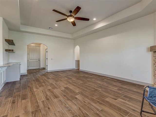 1209 Jozie Way, Tuttle, OK 73089 - unfurnished living room with arched walkways, a ceiling fan, wood finished floors, and a raised ceiling