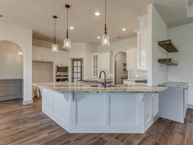 1209 Jozie Way, Tuttle, OK 73089 - kitchen with arched walkways, open shelves, dark wood finished floors, a sink, and stainless steel appliances