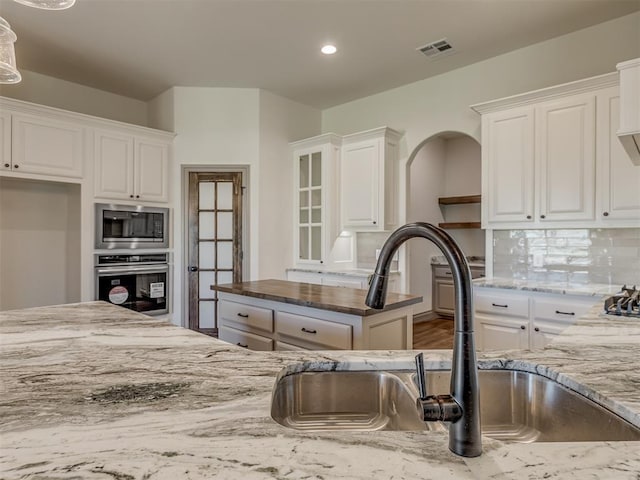 1209 Jozie Way, Tuttle, OK 73089 - kitchen featuring a sink, light stone counters, white cabinets, and stainless steel appliances