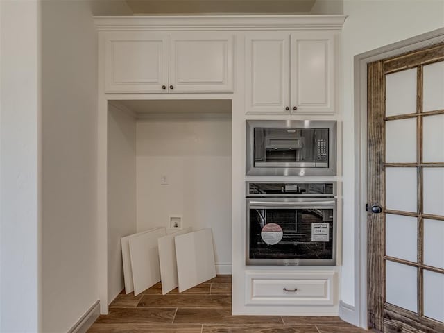 1209 Jozie Way, Tuttle, OK 73089 - kitchen with dark wood-style flooring, built in microwave, baseboards, stainless steel oven, and white cabinetry