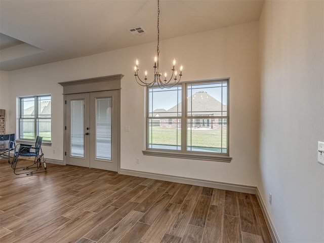 1209 Jozie Way, Tuttle, OK 73089 - unfurnished dining area featuring visible vents, wood finished floors, a notable chandelier, and a healthy amount of sunlight