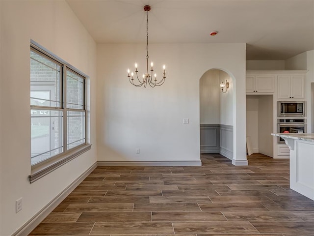 1209 Jozie Way, Tuttle, OK 73089 - unfurnished dining area featuring arched walkways, plenty of natural light, and dark wood-type flooring