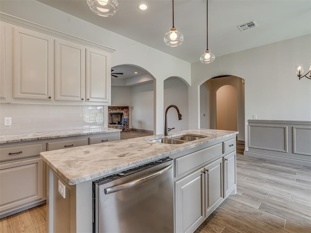 1212 Jaden Blvd, Tuttle, OK 73089 - kitchen featuring stainless steel dishwasher, a sink, arched walkways, hanging light fixtures, and an island with sink