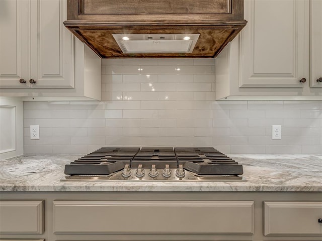 1212 Jaden Blvd, Tuttle, OK 73089 - kitchen with stainless steel gas stovetop, backsplash, exhaust hood, and white cabinets