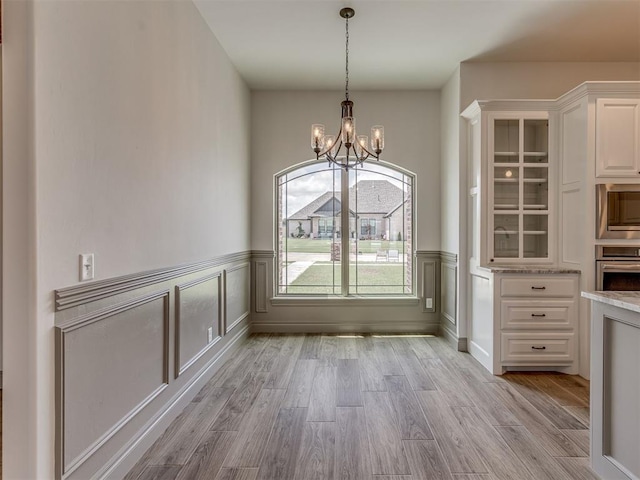 1212 Jaden Blvd, Tuttle, OK 73089 - unfurnished dining area featuring a chandelier, light wood-type flooring, wainscoting, and a decorative wall