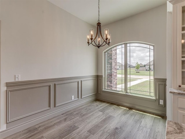 1212 Jaden Blvd, Tuttle, OK 73089 - unfurnished dining area with a chandelier, light wood finished floors, a wainscoted wall, and a decorative wall