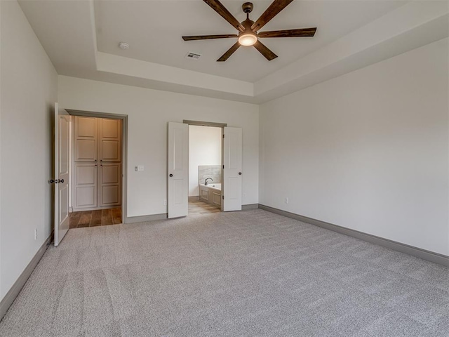 1212 Jaden Blvd, Tuttle, OK 73089 - unfurnished bedroom featuring a raised ceiling, light carpet, baseboards, and connected bathroom
