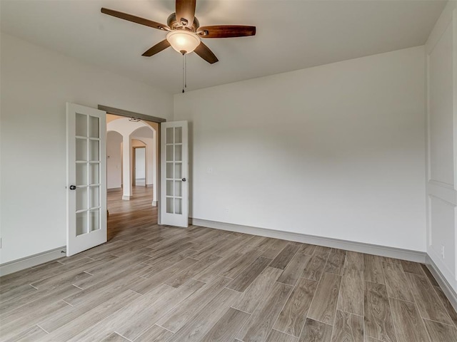 1212 Jaden Blvd, Tuttle, OK 73089 - empty room with french doors, arched walkways, light wood-type flooring, ceiling fan, and baseboards