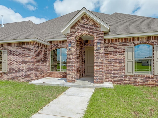 1212 Jaden Blvd, Tuttle, OK 73089 - view of exterior entry with brick siding, roof with shingles, and a yard
