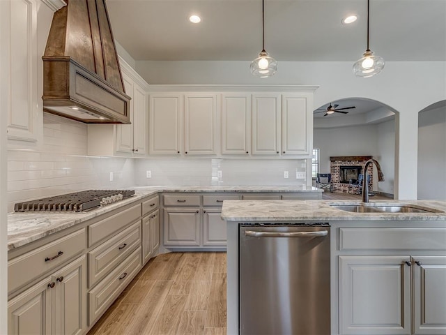 1212 Jaden Blvd, Tuttle, OK 73089 - kitchen with appliances with stainless steel finishes, a sink, premium range hood, a ceiling fan, and decorative backsplash