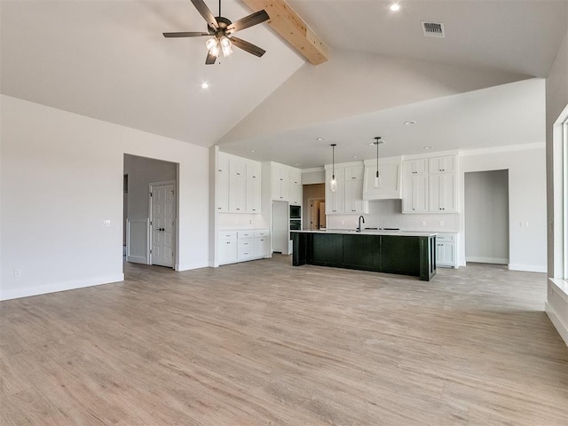 unfurnished living room featuring visible vents, light wood-type flooring, a ceiling fan, and beam ceiling