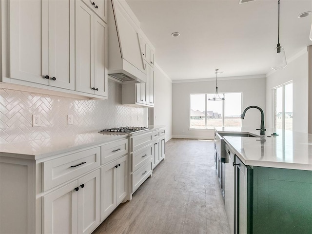 kitchen with light countertops, stainless steel gas cooktop, ornamental molding, premium range hood, and tasteful backsplash