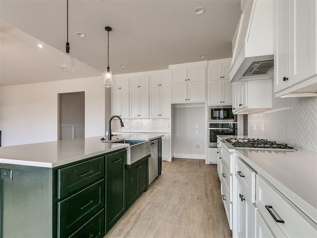 kitchen with green cabinetry, a sink, stainless steel appliances, custom range hood, and white cabinets