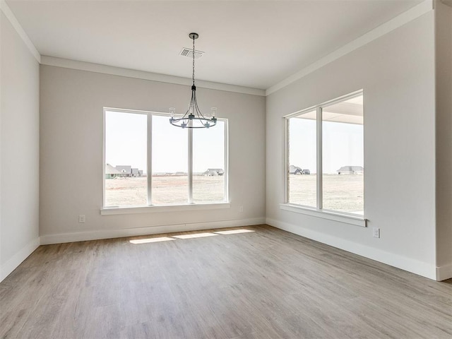 spare room with a notable chandelier, crown molding, wood finished floors, baseboards, and visible vents