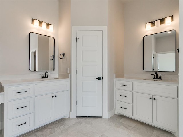 bathroom with marble finish floor, a sink, and two vanities