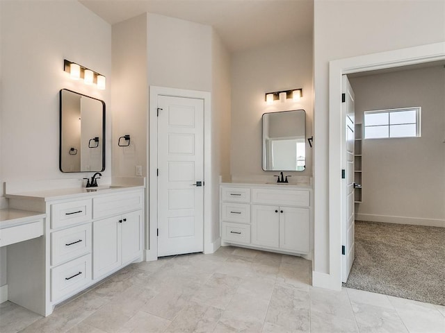 bathroom with baseboards, marble finish floor, a sink, and two vanities