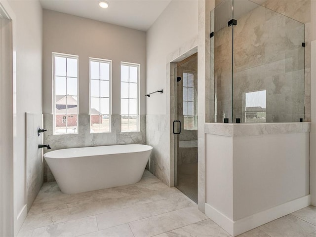 bathroom with a freestanding tub, a stall shower, tile walls, and wainscoting