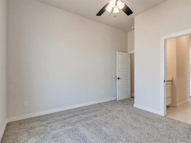 unfurnished bedroom with light carpet, baseboards, connected bathroom, and a ceiling fan