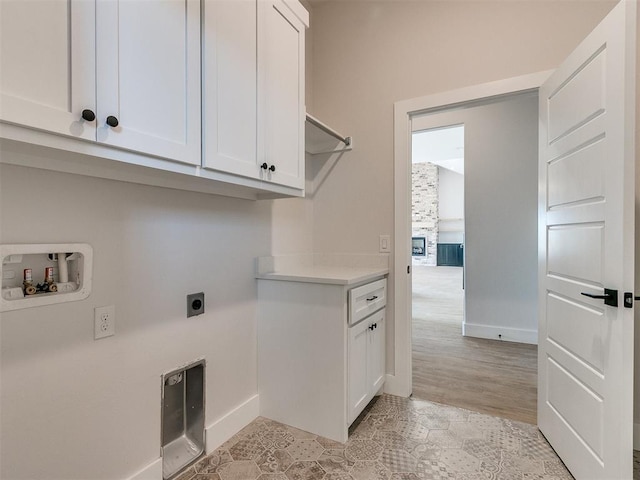 washroom featuring baseboards, hookup for an electric dryer, cabinet space, and hookup for a washing machine