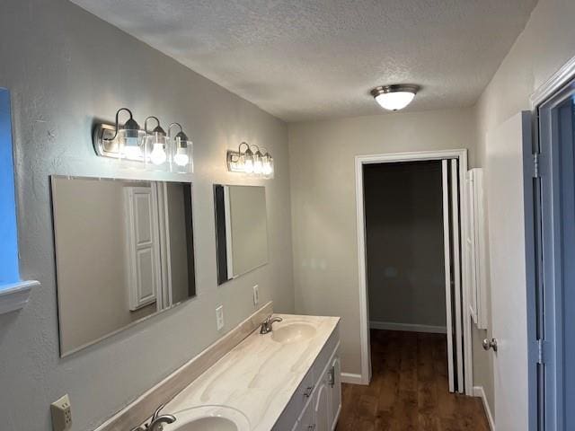 2709 Bishops Dr, Norman, OK 73072 - bathroom with baseboards, a sink, a textured ceiling, double vanity, and wood finished floors