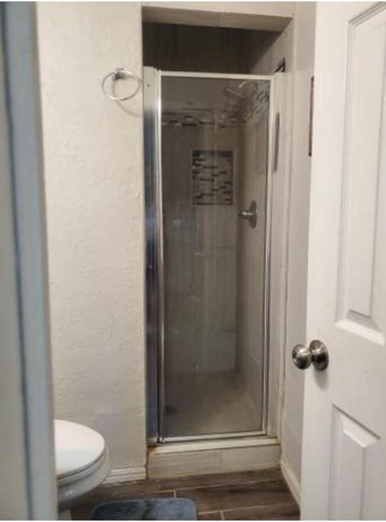 1313 Kingston Dr, Yukon, OK 73099 - full bath featuring a shower stall, a textured wall, toilet, and wood finished floors
