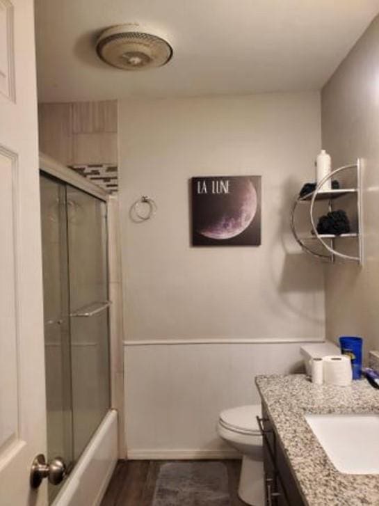 1313 Kingston Dr, Yukon, OK 73099 - full bath featuring shower / bath combination with glass door, vanity, toilet, and wood finished floors