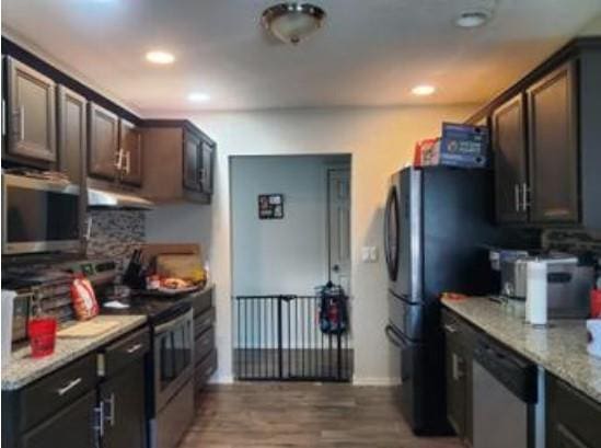 1313 Kingston Dr, Yukon, OK 73099 - kitchen featuring light stone counters, dark wood-style floors, under cabinet range hood, decorative backsplash, and electric stove