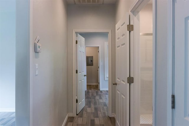 corridor with dark wood-style flooring, baseboards, and electric panel