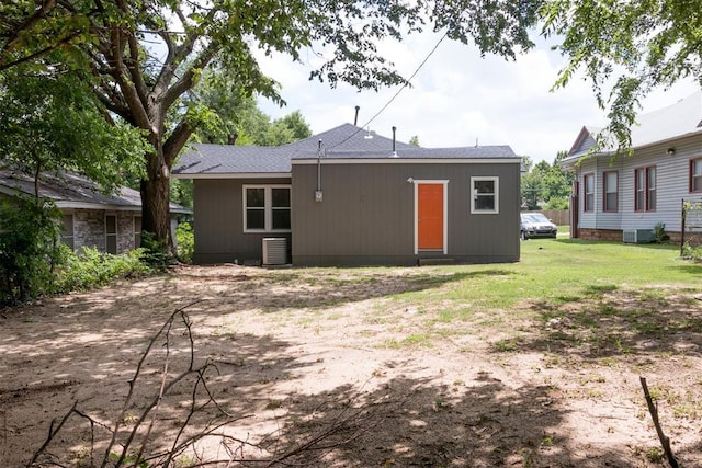 back of property featuring a shingled roof and a lawn
