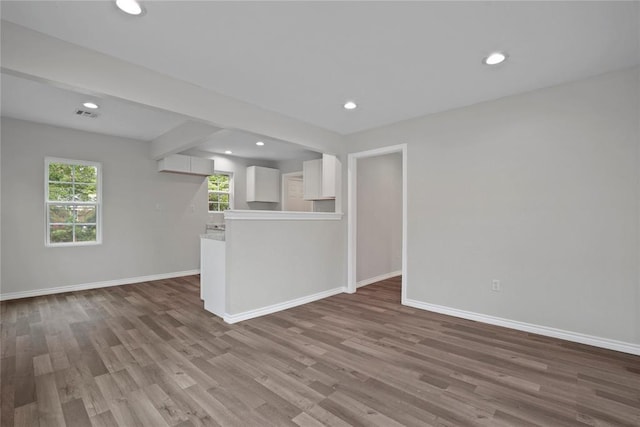 unfurnished living room with wood finished floors, baseboards, visible vents, and recessed lighting