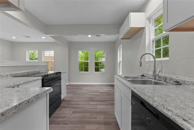 kitchen with baseboards, light countertops, black appliances, a sink, and wood finished floors