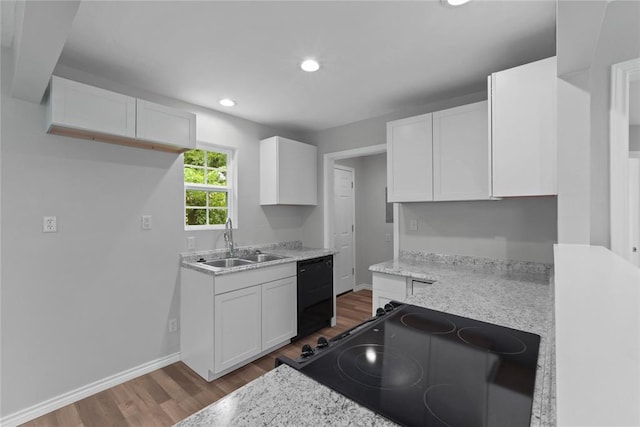 kitchen with baseboards, white cabinets, black appliances, a sink, and wood finished floors