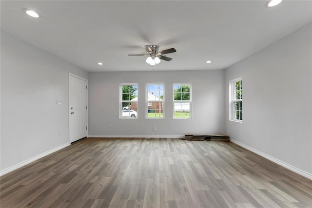 empty room with wood finished floors, ceiling fan, baseboards, and recessed lighting