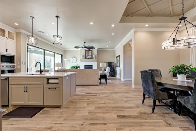 kitchen featuring light wood-type flooring, a fireplace, light countertops, appliances with stainless steel finishes, and a sink