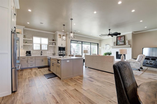 kitchen with open shelves, open floor plan, light countertops, appliances with stainless steel finishes, and light wood-type flooring