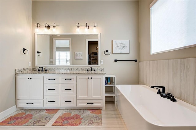 full bath featuring a sink, double vanity, and a soaking tub