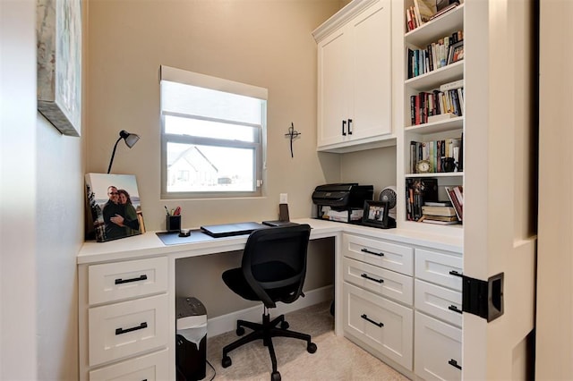 office space with light colored carpet and built in study area