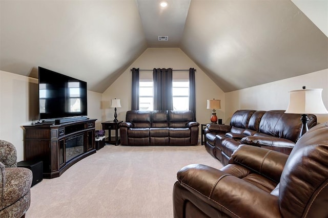 living room featuring light carpet, a glass covered fireplace, vaulted ceiling, and visible vents