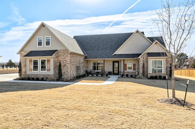 craftsman-style home with roof with shingles, brick siding, and fence