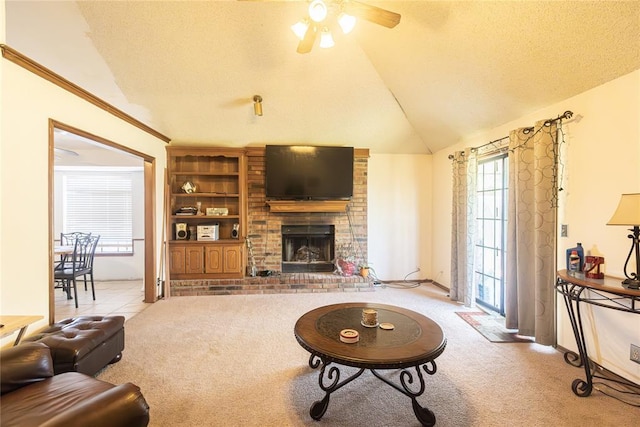 carpeted living room featuring a textured ceiling, a ceiling fan, vaulted ceiling, and a brick fireplace