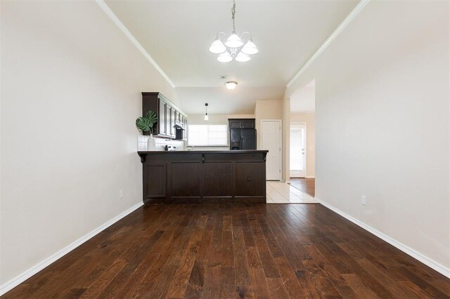 5309 SE 78th St, Oklahoma City, OK 73135 - kitchen with black fridge with ice dispenser, a chandelier, a peninsula, dark wood-style flooring, and ornamental molding