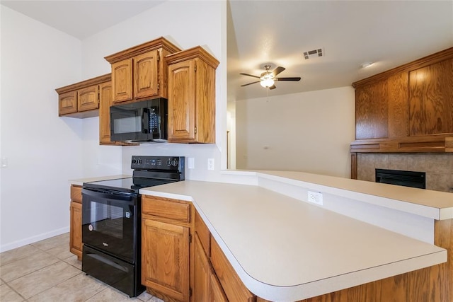 1417 Mayer Dr, Yukon, OK 73099 - kitchen with black appliances, a peninsula, light countertops, ceiling fan, and a tiled fireplace