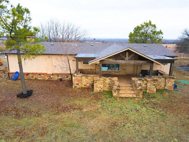 rear view of house featuring roof with shingles